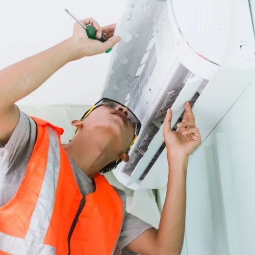 Technicien en train de réparer et régler un climatiseur à Paris